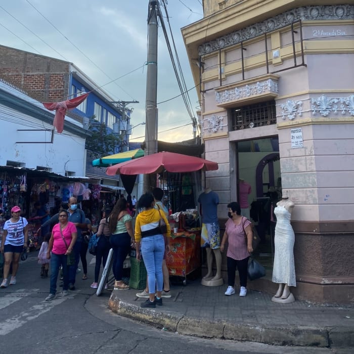 people gathering in a street buying El Salvador